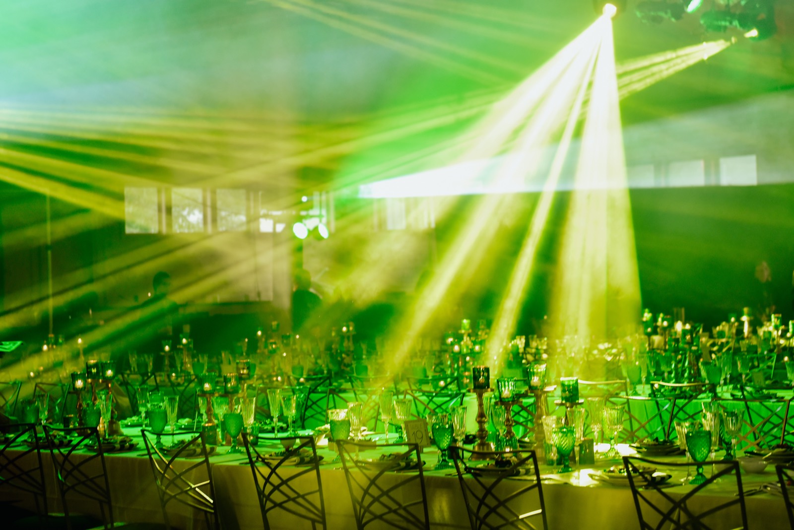 A banquet room set for dinner, under green stage light.